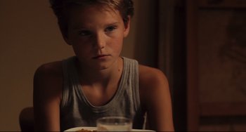 Movie still from “Tomboy” (2011), directed by Céline Sciamma – A boy sitting at a table with a plate of food in front of him; Close Up shot, Over the shoulder angle