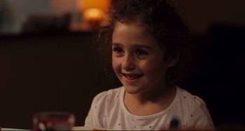 Movie still from “Tomboy” (2011), directed by Céline Sciamma – A little girl sitting at a table with a glass of wine; Close Up shot, Over the shoulder angle
