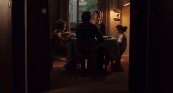 Movie still from “Tomboy” (2011), directed by Céline Sciamma – Three people sitting at a table in a room; Medium shot, Over the shoulder angle