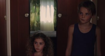 Movie still from “Tomboy” (2011), directed by Céline Sciamma – Two young girls standing next to each other in front of a window; Medium shot, Over the shoulder angle