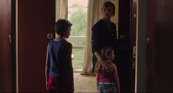 Movie still from “Tomboy” (2011), directed by Céline Sciamma – A woman and two young children standing in front of an open door; Medium shot, Over the shoulder angle
