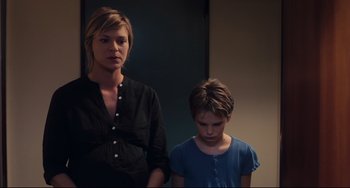 Movie still from “Tomboy” (2011), directed by Céline Sciamma – A woman standing next to a young girl in front of a mirror; Medium shot, Low angle