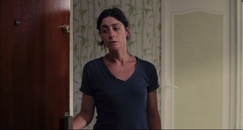 Movie still from “Tomboy” (2011), directed by Céline Sciamma – A woman standing in front of a door looking sad; Medium shot, Over the shoulder angle