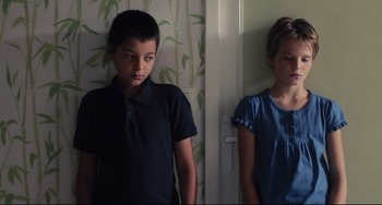 Movie still from “Tomboy” (2011), directed by Céline Sciamma – A boy and a girl standing next to each other in front of a door; Medium shot, Low angle