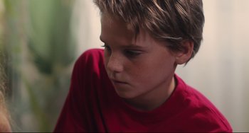 Movie still from “Tomboy” (2011), directed by Céline Sciamma – A boy in a red shirt is looking down; Close Up shot, High angle