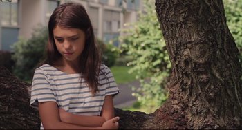 Movie still from “Tomboy” (2011), directed by Céline Sciamma – A young girl leaning against a tree in a park; Close Up shot, Low angle