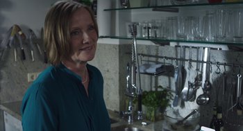 A woman standing in front of a sink in a kitchen