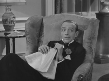 Movie still from “Top Hat” (1935), directed by Mark Sandrich – A black and white photo of a man sitting in a chair holding a newspaper; Medium shot, High angle
