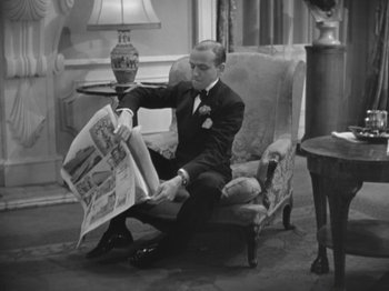 Movie still from “Top Hat” (1935), directed by Mark Sandrich – A black and white photo of a man sitting in a chair reading a newspaper; Medium shot, High angle