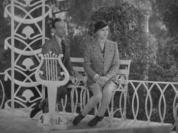 Movie still from “Top Hat” (1935), directed by Mark Sandrich – A man and a woman sitting on a bench in front of a lyre; Wide shot, High angle