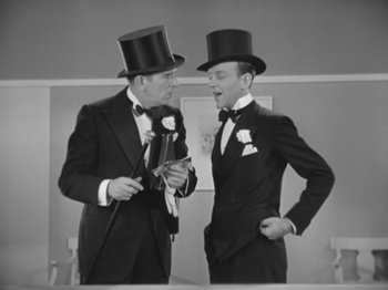 Movie still from “Top Hat” (1935), directed by Mark Sandrich – Two men in top hats and suits talking to each other in front of a mirror; Medium shot, Low angle