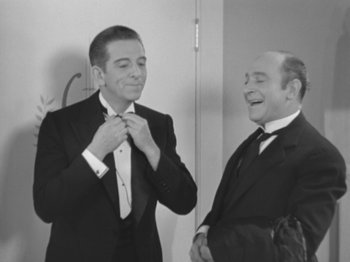 Movie still from “Top Hat” (1935), directed by Mark Sandrich – Two men in tuxedos are smiling while one of them is adjusting his tie; Medium shot, Over the shoulder angle