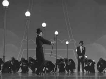 Movie still from “Top Hat” (1935), directed by Mark Sandrich – A group of men standing in front of a light pole; Wide shot, Low angle