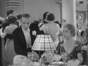 Movie still from “Top Hat” (1935), directed by Mark Sandrich – A black and white photo of a man and a woman at a table; Medium shot, Over the shoulder angle