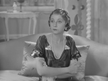 Movie still from “Top Hat” (1935), directed by Mark Sandrich – A woman sitting on a couch with her arms crossed; Close Up shot, High angle