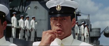 Movie still from “Tora! Tora! Tora!” (1970), directed by Kinji Fukasaku – A man in a sailor's uniform is smoking a cigarette; Close Up shot, Low angle