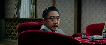 Movie still from “Tora! Tora! Tora!” (1970), directed by Kinji Fukasaku – An older man sitting on a red chair; Close Up shot, Over the shoulder angle