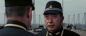 Movie still from “Tora! Tora! Tora!” (1970), directed by Kinji Fukasaku – A man in a military uniform is looking at another man in a uniform; Close Up shot, Over the shoulder angle