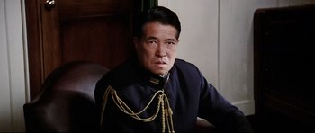 Movie still from “Tora! Tora! Tora!” (1970), directed by Kinji Fukasaku – A man in a uniform sitting in front of a wall; Close Up shot, Low angle