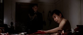 Movie still from “Tora! Tora! Tora!” (1970), directed by Kinji Fukasaku – A man sitting at a table in front of another man; Medium shot, Low angle