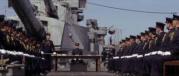 Movie still from “Tora! Tora! Tora!” (1970), directed by Kinji Fukasaku – A group of men standing next to each other on a dock; Wide shot, Low angle