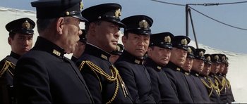 Movie still from “Tora! Tora! Tora!” (1970), directed by Kinji Fukasaku – A group of men in military uniforms standing next to each other; Medium shot, Low angle
