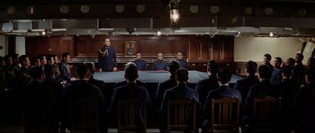 Movie still from “Tora! Tora! Tora!” (1970), directed by Kinji Fukasaku – A group of men sitting at a table in front of a judge; Wide shot, High angle