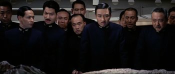 Movie still from “Tora! Tora! Tora!” (1970), directed by Kinji Fukasaku – A group of men standing next to each other in front of a table; Medium shot, High angle