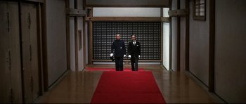 Movie still from “Tora! Tora! Tora!” (1970), directed by Kinji Fukasaku – Two men standing in front of a red carpet; Wide shot, Low angle