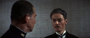 Movie still from “Tora! Tora! Tora!” (1970), directed by Kinji Fukasaku – A man wearing a suit and tie looking at himself in the mirror; Close Up shot, Over the shoulder angle