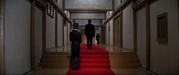 Movie still from “Tora! Tora! Tora!” (1970), directed by Kinji Fukasaku – Two men in suits and one man in a tuxedo walking down a red carpet; Wide shot, Low angle