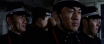 Movie still from “Tora! Tora! Tora!” (1970), directed by Kinji Fukasaku – A man in a police uniform is looking into the camera; Close Up shot, Over the shoulder angle