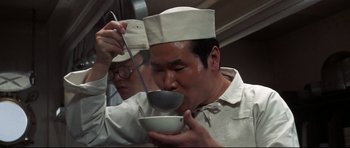 Movie still from “Tora! Tora! Tora!” (1970), directed by Kinji Fukasaku – A man in a chef's hat is drinking from a bowl; Close Up shot, Low angle