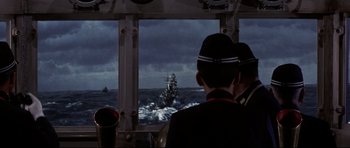 Movie still from “Tora! Tora! Tora!” (1970), directed by Kinji Fukasaku – A group of men in uniforms looking out a window at a ship; Medium shot, High angle