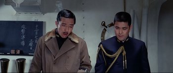 Movie still from “Tora! Tora! Tora!” (1970), directed by Kinji Fukasaku – Two asian men in military garb standing next to each other; Medium shot, Low angle