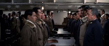 Movie still from “Tora! Tora! Tora!” (1970), directed by Kinji Fukasaku – A group of men standing next to each other in a room; Medium shot, High angle