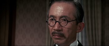 Movie still from “Tora! Tora! Tora!” (1970), directed by Kinji Fukasaku – An older man wearing glasses and wearing a suit; Close Up shot, Over the shoulder angle