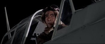 Movie still from “Tora! Tora! Tora!” (1970), directed by Kinji Fukasaku – A man in a pilot's uniform sitting in an airplane cockpit at night; Close Up shot, Low angle