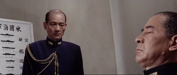 Movie still from “Tora! Tora! Tora!” (1970), directed by Kinji Fukasaku – A man in a black suit with a beard; Medium shot, Low angle