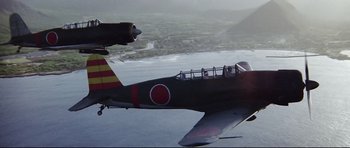 Movie still from “Tora! Tora! Tora!” (1970), directed by Kinji Fukasaku – A fighter jet flying in the air over a body of water; Extreme Wide shot, Low angle