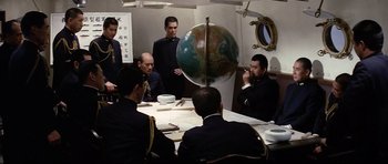 Movie still from “Tora! Tora! Tora!” (1970), directed by Kinji Fukasaku – A group of men sitting around a table with a globe; Wide shot, High angle