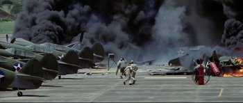 Movie still from “Tora! Tora! Tora!” (1970), directed by Kinji Fukasaku – Two men running on a runway with smoke billowing in the background; Extreme Wide shot, High angle