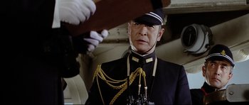 Movie still from “Tora! Tora! Tora!” (1970), directed by Kinji Fukasaku – A man in a uniform is standing in front of another man; Medium shot, Low angle