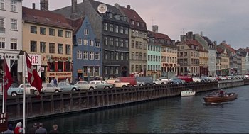 Movie still from “Torn Curtain” (1966), directed by Alfred Hitchcock – Many cars parked along the side of a river; Extreme Wide shot, High angle