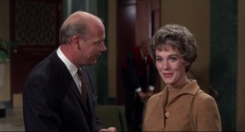 Movie still from “Torn Curtain” (1966), directed by Alfred Hitchcock – An older man standing next to an older woman; Medium shot, Over the shoulder angle