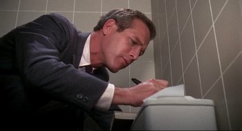 Movie still from “Torn Curtain” (1966), directed by Alfred Hitchcock – A man in a business suit writing on a piece of paper; Close Up shot, Low angle