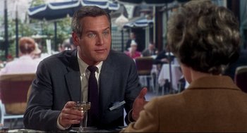 Movie still from “Torn Curtain” (1966), directed by Alfred Hitchcock – A man sitting at a table in front of a glass of wine; Close Up shot, Over the shoulder angle