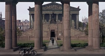 Movie still from “Torn Curtain” (1966), directed by Alfred Hitchcock – A person standing in front of a building with columns; Extreme Wide shot, High angle