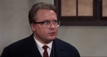 Movie still from “Torn Curtain” (1966), directed by Alfred Hitchcock – A person wearing glasses and a suit; Close Up shot, Over the shoulder angle