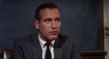 Movie still from “Torn Curtain” (1966), directed by Alfred Hitchcock – A man in a suit and tie sitting in front of a wall; Close Up shot, Low angle